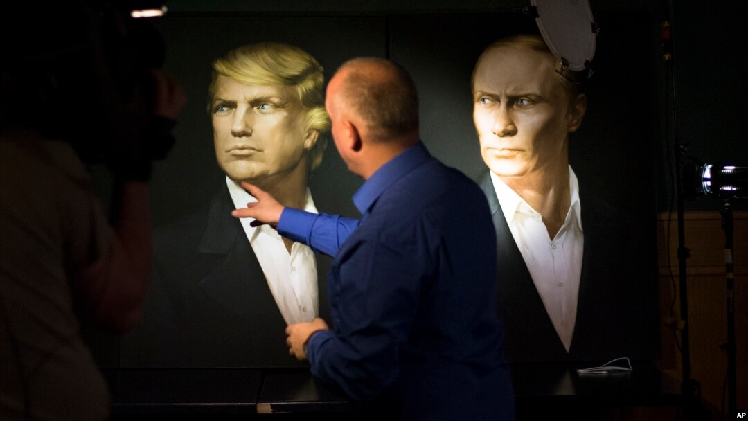 A journalist points at a portrait of U.S. President-elect Donald Trump, with a portrait of Russian President Vladimir Putin at right, during a live telecast of the U.S. presidential election in the Union Jack pub in Moscow, Russia, Nov. 9, 2016. 
