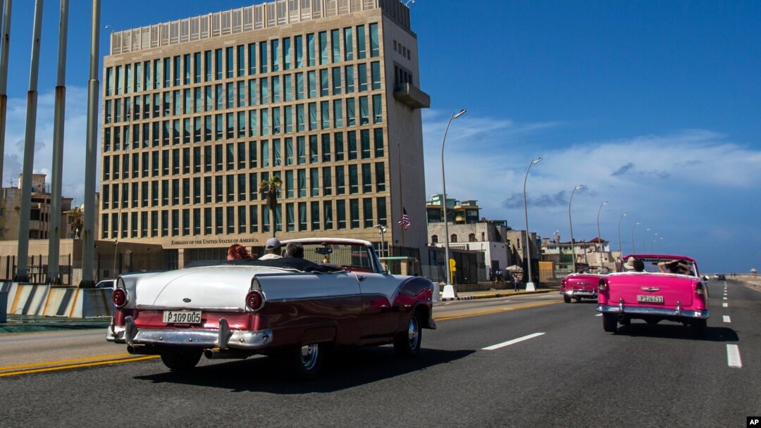 ARCHIVO- Turistas pasean en convertibles clásicos en el Malecón de La Habana frente al edificio de la Embajada de EE.UU. Octubre 3 de 2017. El Departamento de Estado informó que otro de sus empleados en la misión diplomática ha sido afectado por una misteriosa dolencia cuyo origen se desconoce.