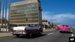 ARCHIVO- Turistas pasean en convertibles clásicos en el Malecón de La Habana frente al edificio de la Embajada de EE.UU. Octubre 3 de 2017. El Departamento de Estado informó que otro de sus empleados en la misión diplomática ha sido afectado por una misteriosa dolencia cuyo origen se desconoce.