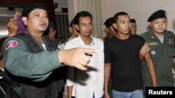 Activists (C) of the Cambodia National Rescue Party (CNRP) are escorted by police officers as they leave the Municipal Court of Phnom Penh August 5, 2015. A Cambodian court on Wednesday indicted two opposition party members for insurrection during a protest a year ago, a decision that could weigh heavily on a shaky political truce nearing the brink of collapse. 