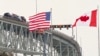 FILE - The US and Canadian flags fly on the US side of the St. Clair River near the Bluewater Bridge border crossing between Sarnia, Ontario and Port Huron, Michigan on Jan. 29, 2025.