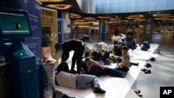 FILE - People from Tajikistan wait for a plane to return to their home country at the Vnukovo international airport, near Moscow, March 24, 2020. Hundreds were struggling to return home after flights were canceled due to the coronavirus.