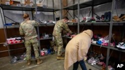 Seorang pengungsi asal Afghanistan tampak mencari sepatu yang merupakan hasil donasi pada pusat donasi di pangkalan militer Fort McCoy, Wisconsin, AS, pada 30 September 2021. (Foto: AP/Barbara Davidson)