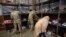 Seorang pengungsi asal Afghanistan tampak mencari sepatu yang merupakan hasil donasi pada pusat donasi di pangkalan militer Fort McCoy, Wisconsin, AS, pada 30 September 2021. (Foto: AP/Barbara Davidson)