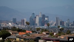 Homes sit on a hilltop with a view of the downtown Los Angeles skyline, June 10, 2021, in Los Angeles.