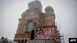 A screen streams the consacration service of the Romanian People's Salvation Cathedral still under construction in Bucharest, Nov. 25, 2018. 