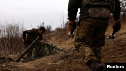 Украинские солдаты готовятся выпустить минометный снаряд по передовой позиции близ Бахмута, в Донецкой области, Украина, 16 марта 2023 года.