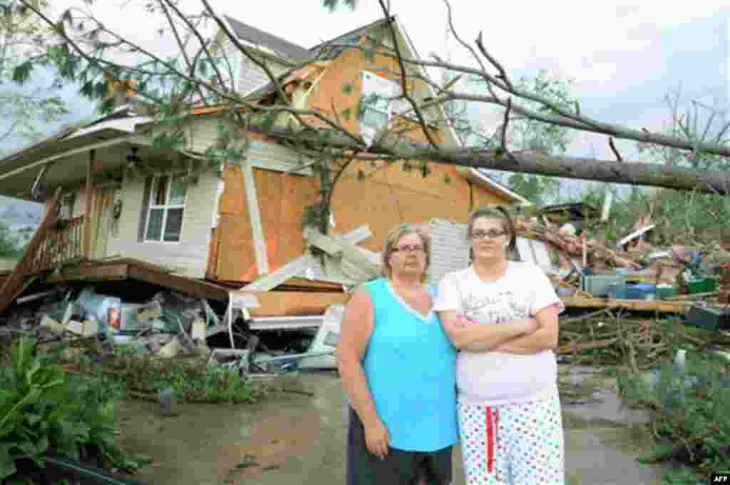 Diane and Ashley Guyton, victims of the tornado that ripped through Concord, Ala., pose for a photo in front of their house, Thursday, April 28, 2011. The gray truck, underneath the home, saved their lives. Diane and Ashley ran with their family to the ba