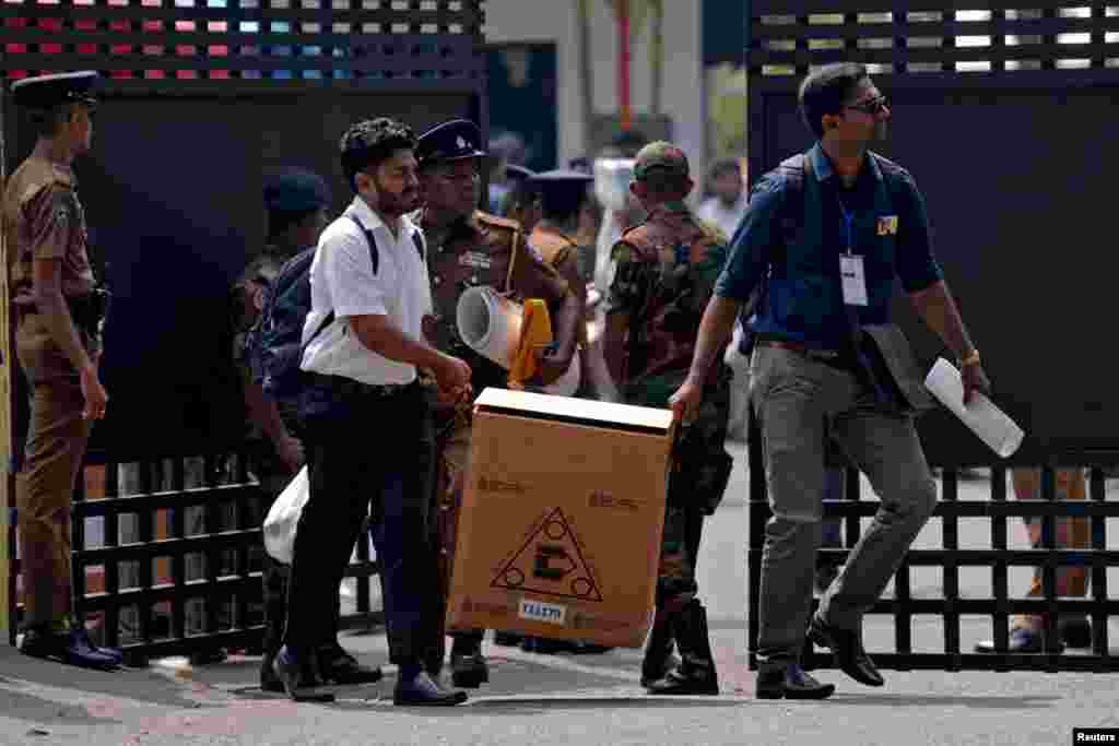 Polling officials and police officers carry election materials a day before the Parliamentary Election, in Colombo, Sri Lanka.