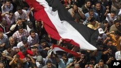 Egyptians shout as they wave a giant flag during a demonstration at Tahrir Square, Cairo, April 1, 2011, to call for the military government to harshly punish members of ex-President Hosni Mubarak's former administration