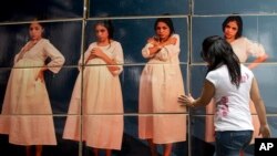 FILE - A woman adjusts cardboard boxes assembled to form a display highlighting the issue of teenage pregnancy outside the National Population Council's headquarters in Mexico City, May 29, 2014. 