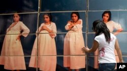 FILE -A woman adjusts cardboard boxes assembled to form a display highlighting the issue of teenage pregnancy outside the National Population Council's headquarters in Mexico City, Thursday, May 29, 2014. 