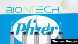 FILE - Syringes are seen in front of displayed Biontech and Pfizer logos in this illustration taken November 10, 2020.