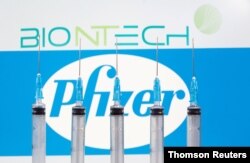 FILE - Syringes are seen in front of displayed Biontech and Pfizer logos in this illustration taken November 10, 2020.