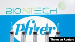 FILE - Syringes are seen in front of displayed Biontech and Pfizer logos in this illustration taken November 10, 2020.