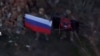 A soldier holds up a Russian flag in Kurakhove, Donetsk Region, Ukraine in this screen grab taken from a social media video released on Jan. 5, 2025, obtained by Reuters. (Social Media/via REUTERS) 