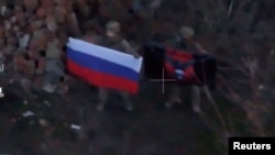 A soldier holds up a Russian flag in Kurakhove, Donetsk Region, Ukraine in this screen grab taken from a social media video released on January 5, 2025, obtained by Reuters. (Social Media/via REUTERS)