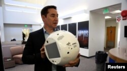 FILE - Bret Greenstein, IBM Global Vice President of Watson Internet of Things Offerings, holds a clone of an artificial intelligence bot named CIMON, at the Kennedy Space Center in Florida, June 28, 2018. 