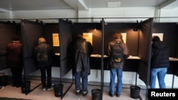 People vote in voting booths during early voting in the Lithuanian general elections, in Vilnius, Lithuania, Oct. 8, 2024.