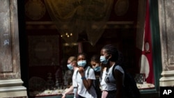 FILE - Children wear protective face masks as they walk in the historical center of Brussels, Aug. 12, 2020. 