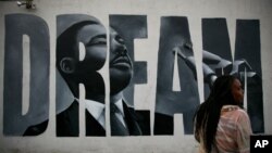 Lorinda Lacy, 45, stands outside her party store painted with a mural depicting Martin Luther King Jr., in the Watts neighborhood of Los Angeles, June 30, 2020.