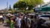 People wait in line to receive free meals at a distribution center for those affected by the Maui fires at Honokawai Beach Park in Napili-Honokowai, west of Maui, Hawaii, Aug. 14, 2023.