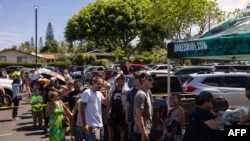 People wait in line to receive free meals at a distribution center for those affected by the Maui fires at Honokawai Beach Park in Napili-Honokowai, west of Maui, Hawaii, Aug. 14, 2023.