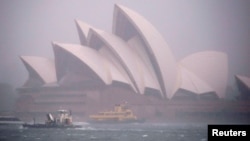 FILE - Ferries and boats pass in front of the Sydney Opera House as strong winds and heavy rain hit the city of Sydney, Australia, Nov. 28, 2018. 