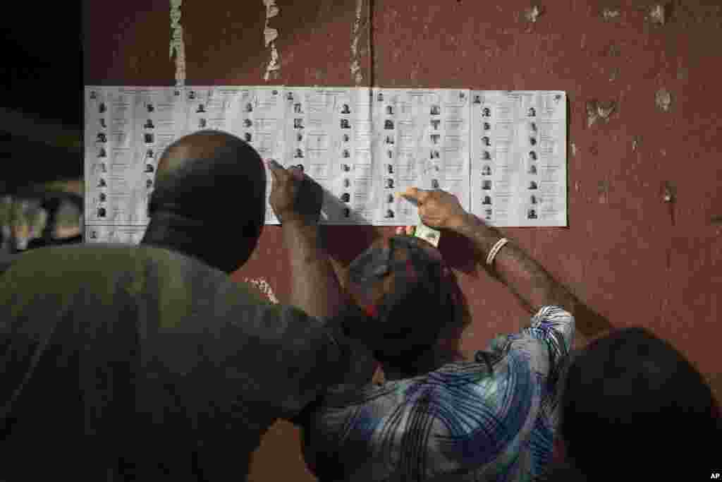 People check for their names on the voters registration list during the presidential elections in Agulu, Nigeria, Saturday, Feb. 25, 2023.