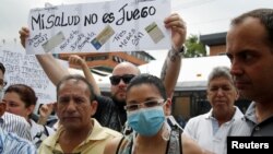 FILE - People hold a sign that reads "My health is not a game" during a protest against shortages of medicines outside a pharmacy in Caracas, Venezuela June 29, 2016.