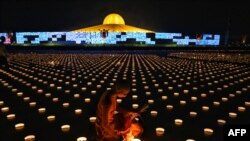 A Buddhist monk lights candles to commemorate Visakha Bucha Day or Vesak Day, a celebration of the birth, enlightenment and death of the Lord Buddha, held on the full moon of the third lunar month in the Buddhist calendar, at Wat Dhammakaya Buddhist temple in Bangkok, Thailand.