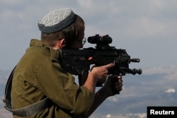 Seorang tentara Israel mengintip menggunakan teropong senapan ke arah Lebanon selatan dari Israel, di tengah ketegangan antara Hizbullah dan pasukan Israel, 4 November 2024. (Foto: Reuters)