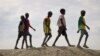 FILE - In this photo taken Dec. 9, 2018, a group of youths walk on top of a small hill of dirt in the United Nations protection of civilians site in Bentiu, South Sudan.
