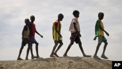 FILE - In this photo taken Dec. 9, 2018, a group of youths walk on top of a small hill of dirt in the United Nations protection of civilians site in Bentiu, South Sudan.