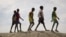 FILE - In this photo taken Dec. 9, 2018, a group of youths walk on top of a small hill of dirt in the United Nations protection of civilians site in Bentiu, South Sudan.