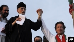 FILE - Pakistan's fiery cleric Tahir-ul-Qadri, second left, and cricketer-turned-politician Imran Khan, right, jointly raise their hands for their supporters during a protest near Prime Minister's home in Islamabad.