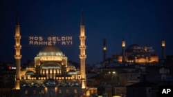 FILE —Light messages installed in the Yeni mosque, or New mosque, left, read in Turkish "Welcome month of mercy," and in Hagia Sophia mosque "There is no God but Allah" ahead of the Muslim holy month of Ramadan, in Istanbul, Turkey, March 10, 2024. 