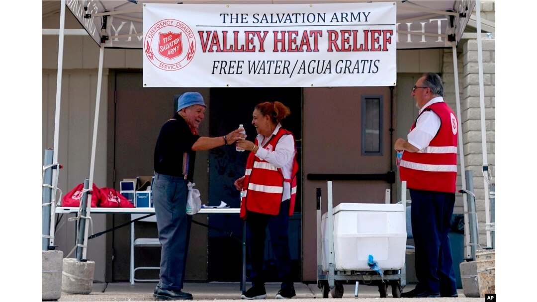 Seorang relawan memberikan air minum kepada seorang pria lansia di Stasiun Bantuan Panas pada 11 Juli 2023 di kota Phoenix, Arizona.
