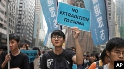 FILE - Protesters with placards and flags against an extradition law march toward the government headquarters in Hong Kong, March 31, 2019.