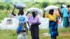 FILE - Women carry bags of maize during a food aid distribution in Mudzi about 230 kilometers northeast of the capital Harare, Zimbabwe, Feb. 20, 2020.