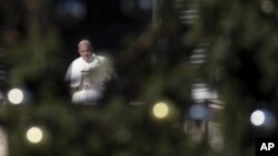 El Papa Francisco, enmarcado por el arbol de Navidad en la Plaza de San Pedro, elogió las escenas de la Natividad como un símbolo de la fe cristiana, AP