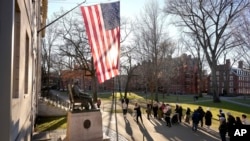 ARCHIVO - Personas tomando fotografías cerca de una estatua de John Harvard, izquierda, en el campus de la Universidad de Harvard, el martes 2 de enero de 2024, en Cambridge, Massachusetts.