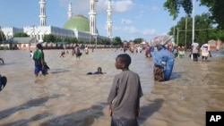 People walk through floodwaters following a dam collapse in Maiduguri, Nigeria, Sept. 10, 2024.