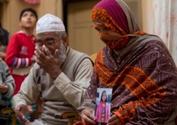 FILE - Nusrat holds a photo of her daughter, Zainab Ansari, who was raped and killed, as her husband, Mohammed Amin in Kasur, sits next to her in Kasur, Pakistan, Jan. 18, 2018.