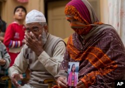 FILE - Nusrat holds a photo of her daughter, Zainab Ansari, who was raped and killed, as her husband, Mohammed Amin in Kasur, sits next to her in Kasur, Pakistan, Jan. 18, 2018.