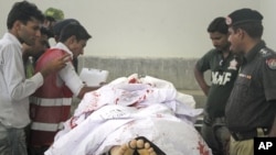 Policemen, rescue workers and the media stand next to the body of the Saudi diplomat who was killed by unidentified gunmen, at a morgue in Karachi's Jinnah hospital, May 16, 2011