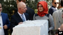 Jeff Bezos, direktè Washington Post la, agoch, Hatice Cengiz, adwat, fiyanse jounalis viktim nan Jamal Kashoggi nan moman yo tap erije yon plak nan mewa jounalis Kashoggi devan konsila Arabi Saoudit la nan Istanbul, Tirki. (Foto: AP/Lefteris Pitarakis) mèkredi 2 oktòb 2019. 