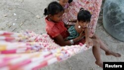 FILE - Children play in a hammock in Broma village in Kratie province, Cambodia, Oct. 22, 2012. 