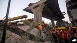 Regu penyelamat berdiri di dekat jembatan yang runtuh di Mumbai, India, 7 Februari 2013. (AP Photo/Rafiq Maqbool). Tiga orang dilaporakn tewas dalam insiden ini.