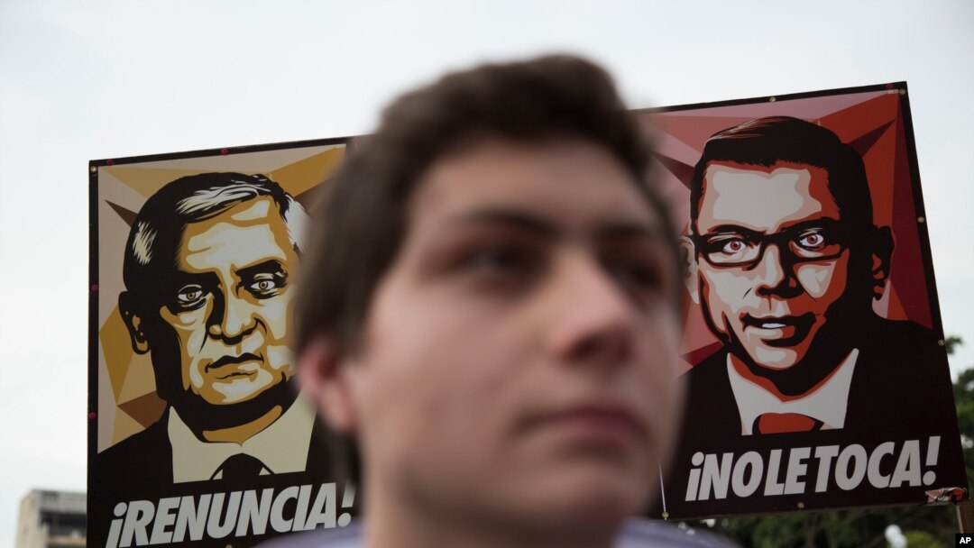 Manifestantes sostienen una pancarta que muestra la imagen del presidente de Guatemala, Otto Pérez Molina, a la izquierda, y Manuel Baldizon, Ciudad de Guatemala, el 13 de julio de 2015. 